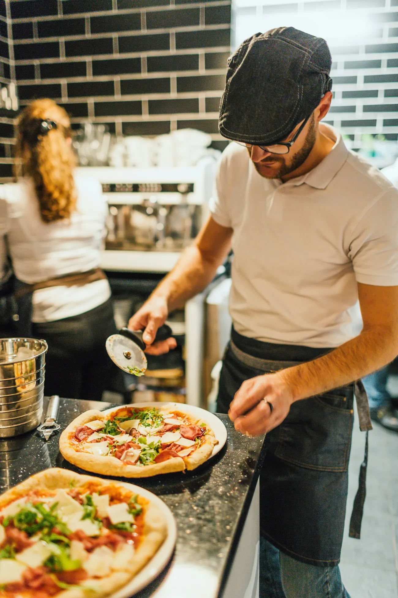 Pizzaiolo skär en nygräddad pizza